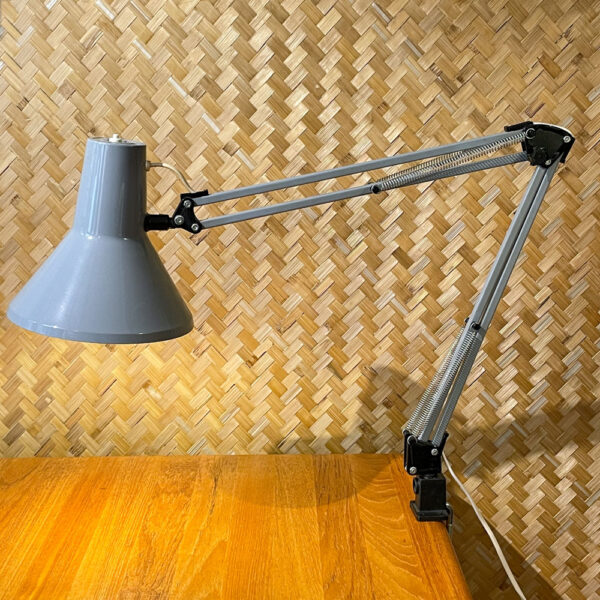 Die Vintage-Schreibtischlampe HCF DVE im freundlichen Industriegrau. Die Lampe stammt aus den 1970er Jahren und bezieht sich auf das klare Design Skandinaviens. Ihr schlankes Design zeigt eine außergewöhnliche Mischung aus Design und Funktionalität. Durch die Federn und die Feststellschraube am Gelenk lässt sich die Lampe verstellen mit einer maximalen Höhe von 88 cm. Die Lampe ist in einem schönen Vintage-Zustand und hat eine schöne Patina. Den Zustand entnehmt bitte den Bildern. Mit ihrer schlanken Form und ihrer dezenten Farbe läßt sich die Lampe super mit anderen Einrichtungsgegenständen kombinieren und ist eine coole Ergänzung für jeden Arbeits- oder Wohnbereich. Die Einstellmöglichkeiten lassen sich anhand ihrer markanten Form erkennen und erfühlen. Der An- und Ausschalter befindet sich am oberen Rand des Lampenschirms.