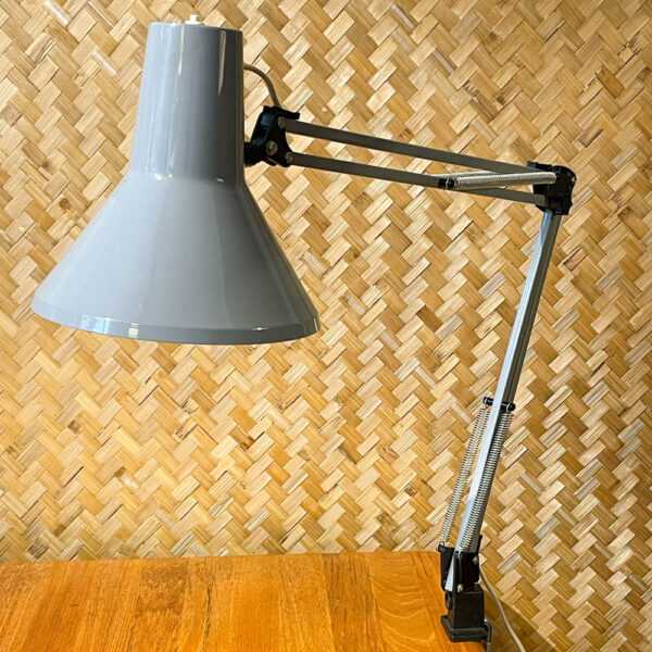 Die Vintage-Schreibtischlampe HCF DVE im freundlichen Industriegrau. Die Lampe stammt aus den 1970er Jahren und bezieht sich auf das klare Design Skandinaviens. Ihr schlankes Design zeigt eine außergewöhnliche Mischung aus Design und Funktionalität. Durch die Federn und die Feststellschraube am Gelenk lässt sich die Lampe verstellen mit einer maximalen Höhe von 88 cm. Die Lampe ist in einem schönen Vintage-Zustand und hat eine schöne Patina. Den Zustand entnehmt bitte den Bildern. Mit ihrer schlanken Form und ihrer dezenten Farbe läßt sich die Lampe super mit anderen Einrichtungsgegenständen kombinieren und ist eine coole Ergänzung für jeden Arbeits- oder Wohnbereich. Die Einstellmöglichkeiten lassen sich anhand ihrer markanten Form erkennen und erfühlen. Der An- und Ausschalter befindet sich am oberen Rand des Lampenschirms.