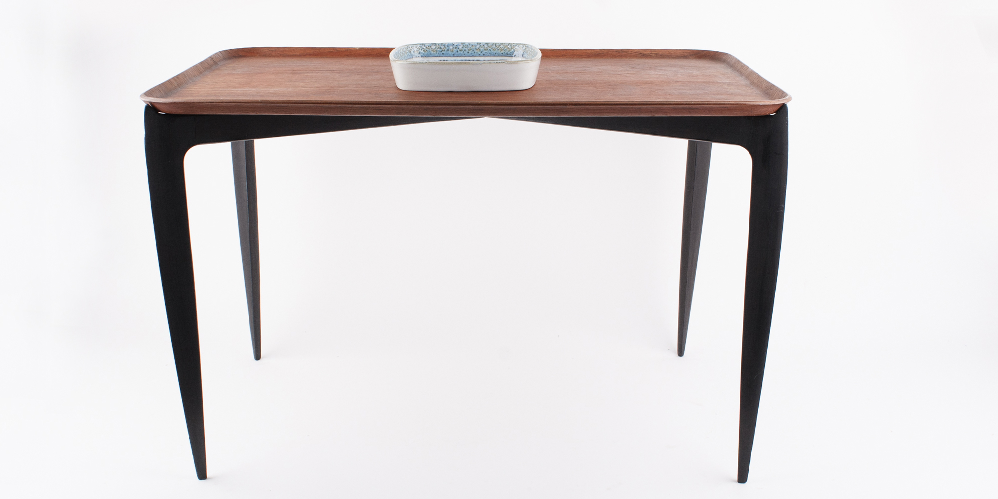 Der platzsparende Klapptisch von Fritz Hansen ist eine Designikone und wurde in den frühen 1960er Jahren entworfen. Das Gestell ist aus schwarz gefärbtem Teakholz. Das Tablett ist ebenfalls aus Teakholz.
