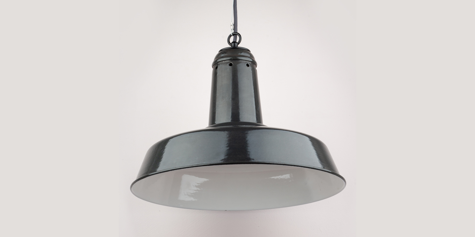 Diese alte Industrielampe war einmal eine Arbeitsplatzlampe. Der Zustand ist top! Die Lampe wurde neu verkabelt mit einem grauen Textilkabel und einem dezenten Drahtseil als Zugentlastung. Der Baldachin ist schwarz pulverbeschichtet und nagelneu. Der Winkel in dem die Lampe strahlt, ist sehr breit und ist perfekt als Esstisch-, oder Küchenlampe. Innen ist die Lampe mit weisser Emaille beschichtet.
