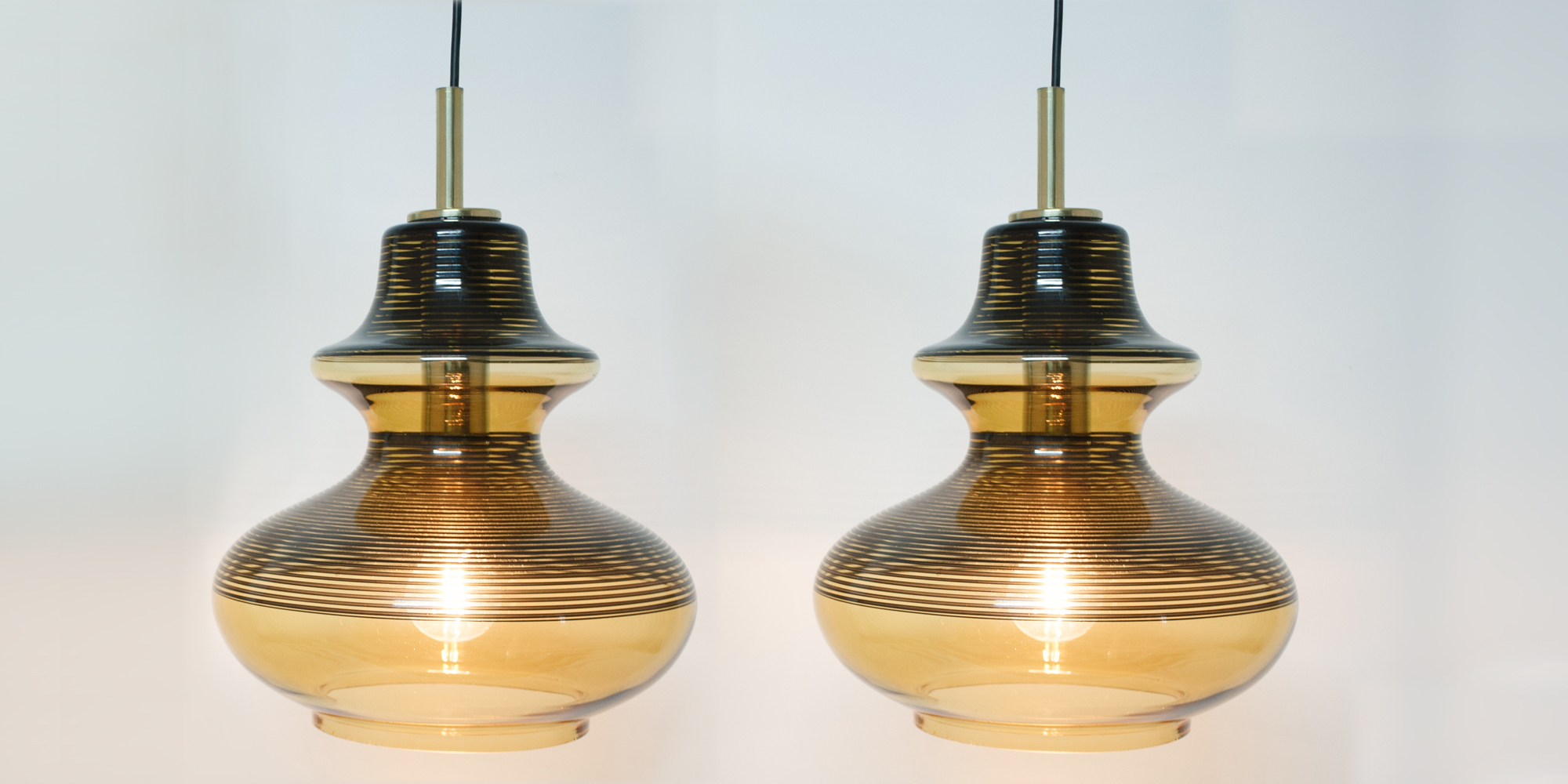 Ein stylisches Lampenpaaraus Rauchglas und schwarzen Ringen. Die schwarzen Ringe werfen ein Streifenmuster an die Wand. Sie sind ein perfektes Paar um über dem Esstisch zu hängen. Höhe 30 cm Breite 40cm