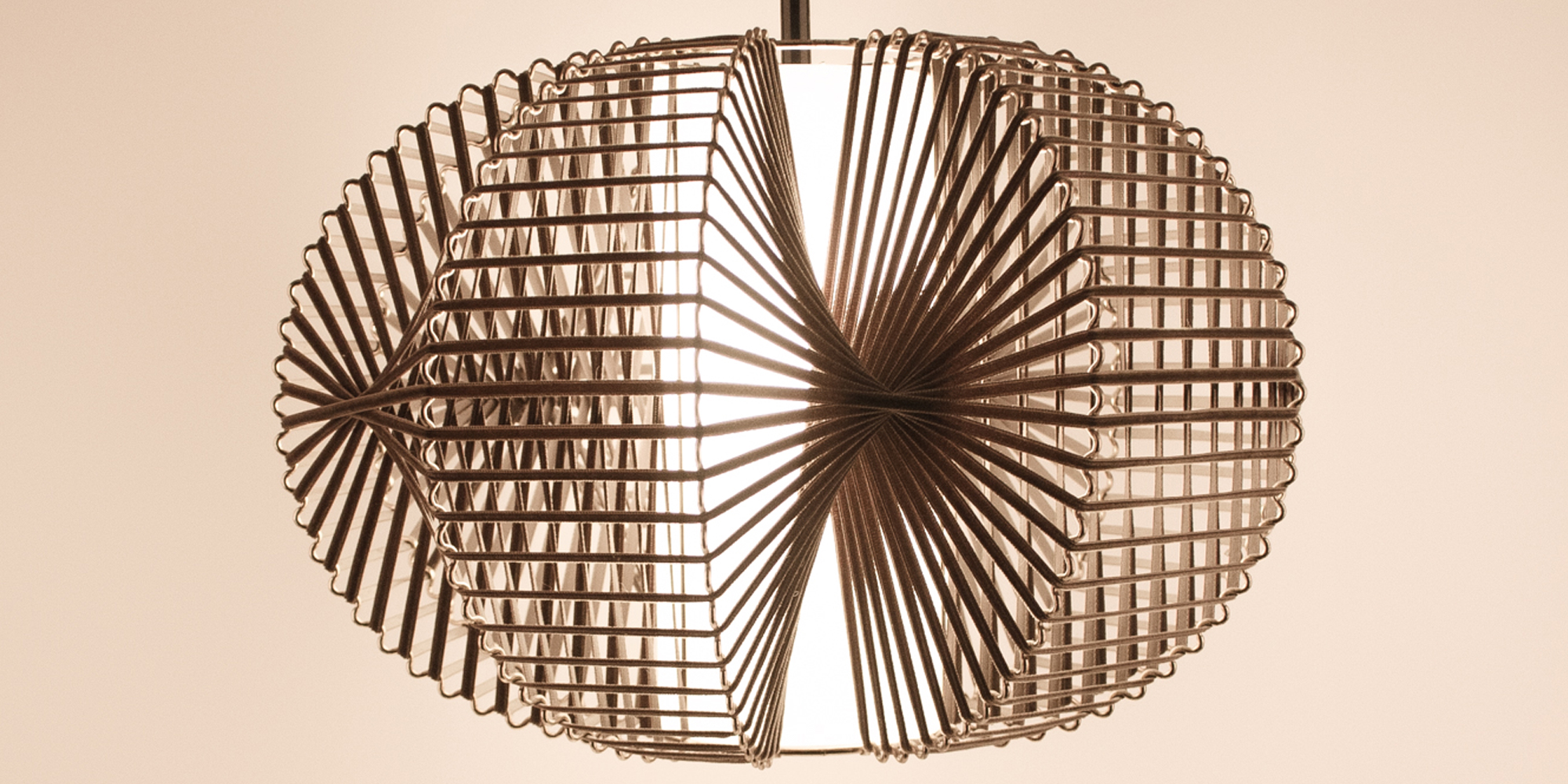 Eine Designlampe, bestehend aus Messing und Samtband. Die Art wie das Samtband auf den wellenartig geformten Draht gebunden ist, wirft ein tolles Licht auf die Zimmerwand. In der Mitte befindet sich ein Papier,das in Zilinderform das Leuchtmittel bedeckt und somit ein angenehmes Licht abgibt. Die Höhe der Lampe ist 30 cm und die breiteste Stelle an der Lampe ist 40 cm.