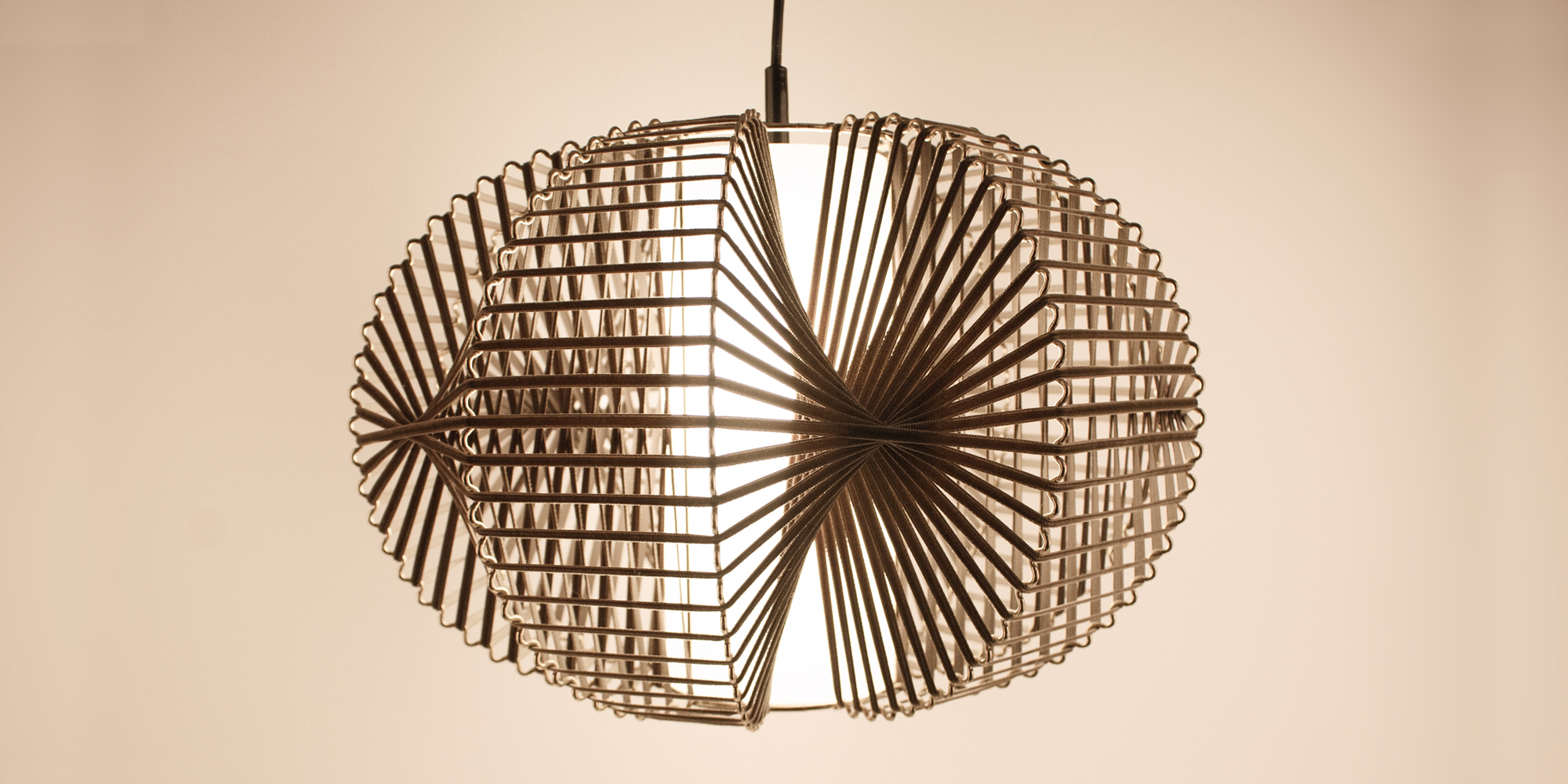 Eine Designlampe, bestehend aus Messing und Samtband. Die Art wie das Samtband auf den wellenartig geformten Draht gebunden ist, wirft ein tolles Licht auf die Zimmerwand. In der Mitte befindet sich ein Papier,das in Zilinderform das Leuchtmittel bedeckt und somit ein angenehmes Licht abgibt. Die Höhe der Lampe ist 30 cm und die breiteste Stelle an der Lampe ist 40 cm.