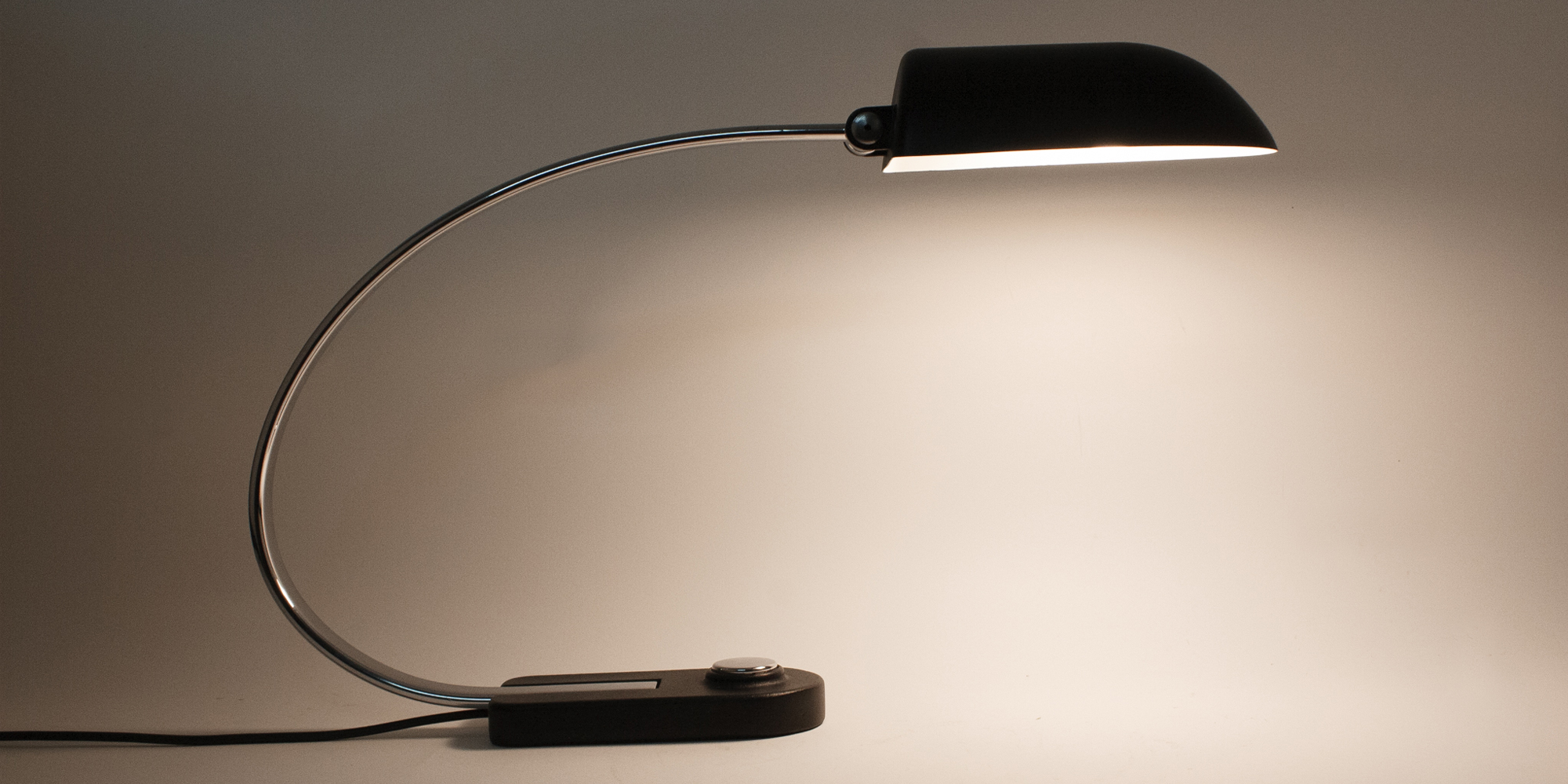 Diese Schreibtischlampe stammt aus der Manufaktur Hillebrand. Das Modell 7620 ist schwarz pulverbeschichtet und Chrom. Das Chrom als auch der schwarze Lack sind komplett neu beschichtet worden. Die Lampe ist in einem Topzustand. Durch ihren grossen Metallbügel hat die Lampe eine sehr elegante Form. Der Druckschalter ist ebenfalls aus Chrom. Der Schirm lässt sich mittels eines Inbusschlüssel verstellen. Der Schirm ist von innen weiss lackiert, sodass das Licht gut reflektieren kann. Höhe 40cm, B 14cm, Tiefe 65cm.