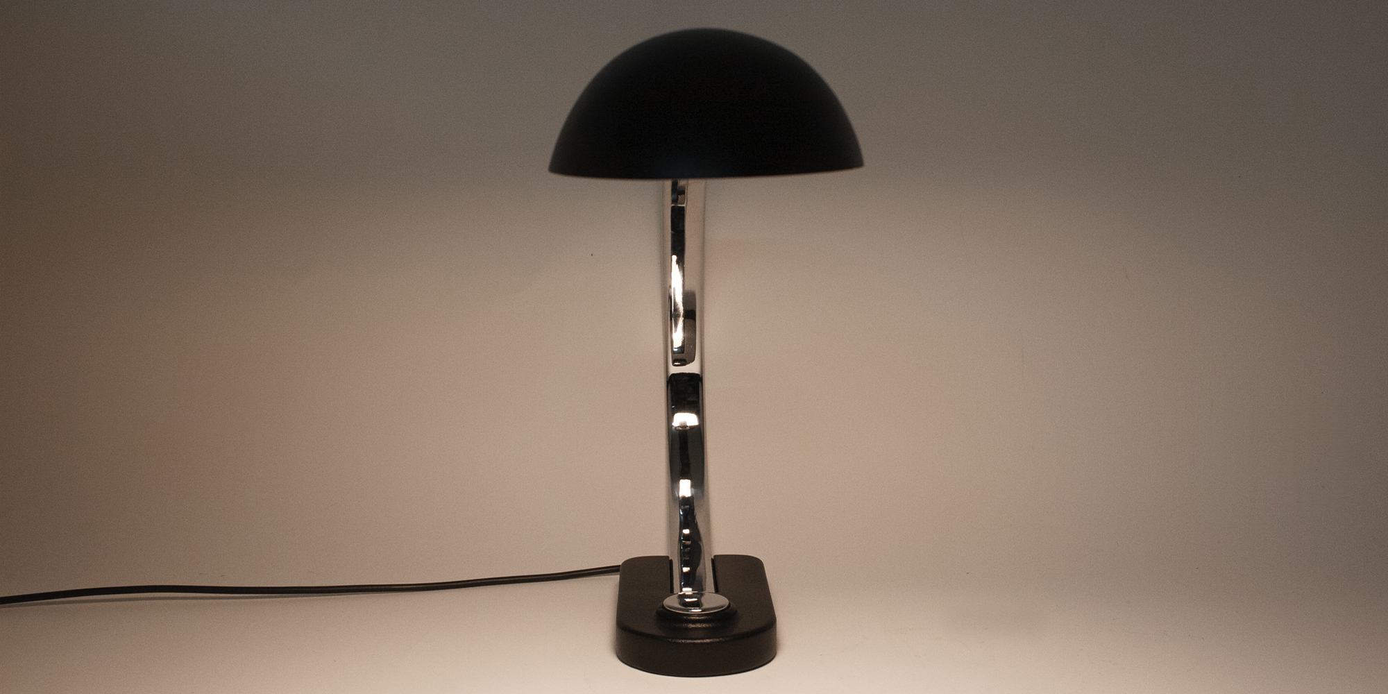 Diese Schreibtischlampe stammt aus der Manufaktur Hillebrand. Das Modell 7620 ist schwarz pulverbeschichtet und Chrom. Das Chrom als auch der schwarze Lack sind komplett neu beschichtet worden. Die Lampe ist in einem Topzustand. Durch ihren grossen Metallbügel hat die Lampe eine sehr elegante Form. Der Druckschalter ist ebenfalls aus Chrom. Der Schirm lässt sich mittels eines Inbusschlüssel verstellen. Der Schirm ist von innen weiss lackiert, sodass das Licht gut reflektieren kann. Höhe 40cm, B 14cm, Tiefe 65cm.