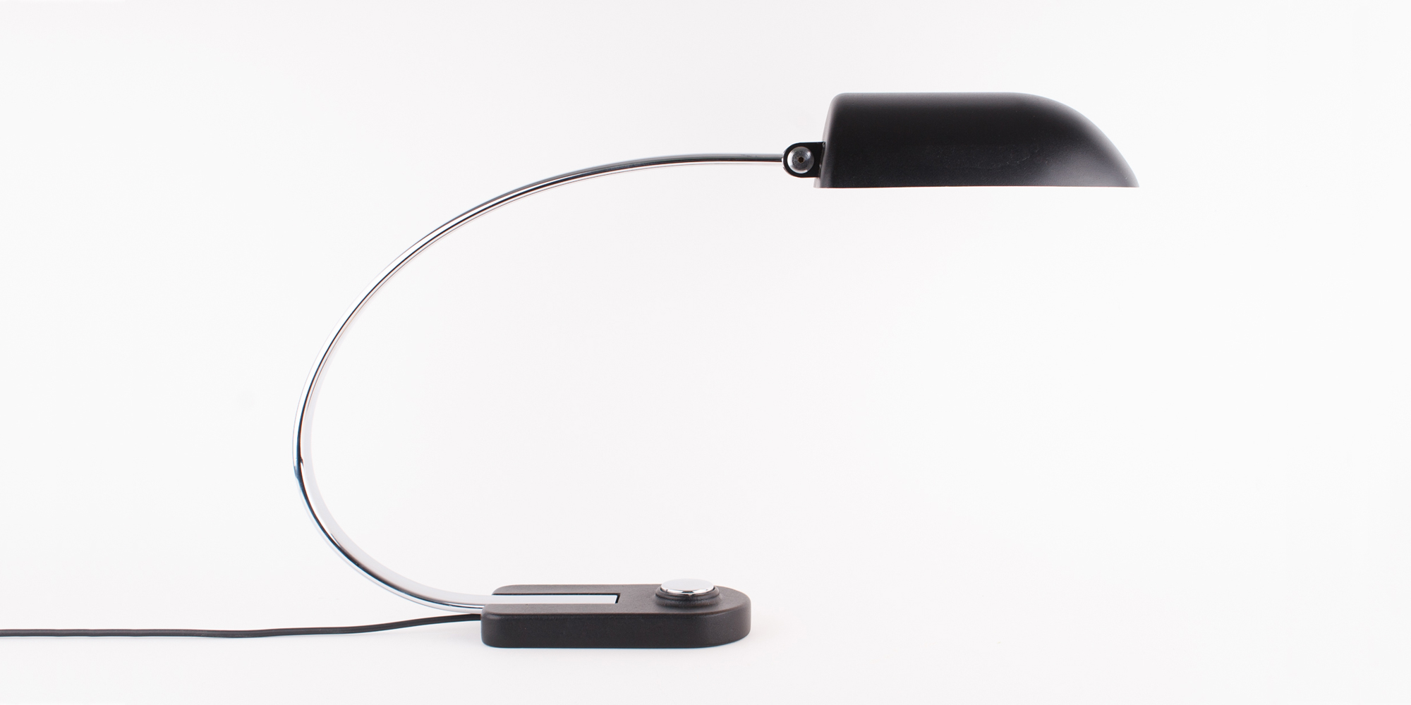 Diese Schreibtischlampe stammt aus der Manufaktur Hillebrand. Das Modell 7620 ist schwarz pulverbeschichtet und Chrom. Das Chrom als auch der schwarze Lack sind komplett neu beschichtet worden. Die Lampe ist in einem Topzustand. Durch ihren grossen Metallbügel hat die Lampe eine sehr elegante Form. Der Druckschalter ist ebenfalls aus Chrom. Der Schirm lässt sich mittels eines Inbusschlüssel verstellen. Der Schirm ist von innen weiss lackiert, sodass das Licht gut reflektieren kann. Höhe 40cm, B 14cm, Tiefe 65cm.