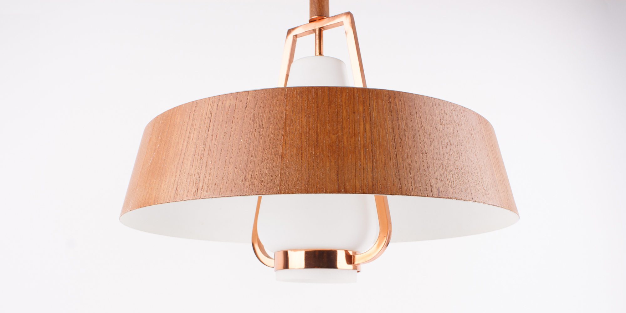 Eine Deckenlampe aus den 1960er Jahren. Das Gestell ist aus Kupfer mit einer Teakfurnierschicht und einem opakem, weissen Glaskorpus, der das Licht auf angenehme Art in den Raum streut. Die Lampe ist extravagant, lässt sich aber durchaus mit modernem Interieur kombinieren. Der Durchmesser der Lampe ist an der breitesten Stelle 40 cm und hat eine Höhe von 34 cm.