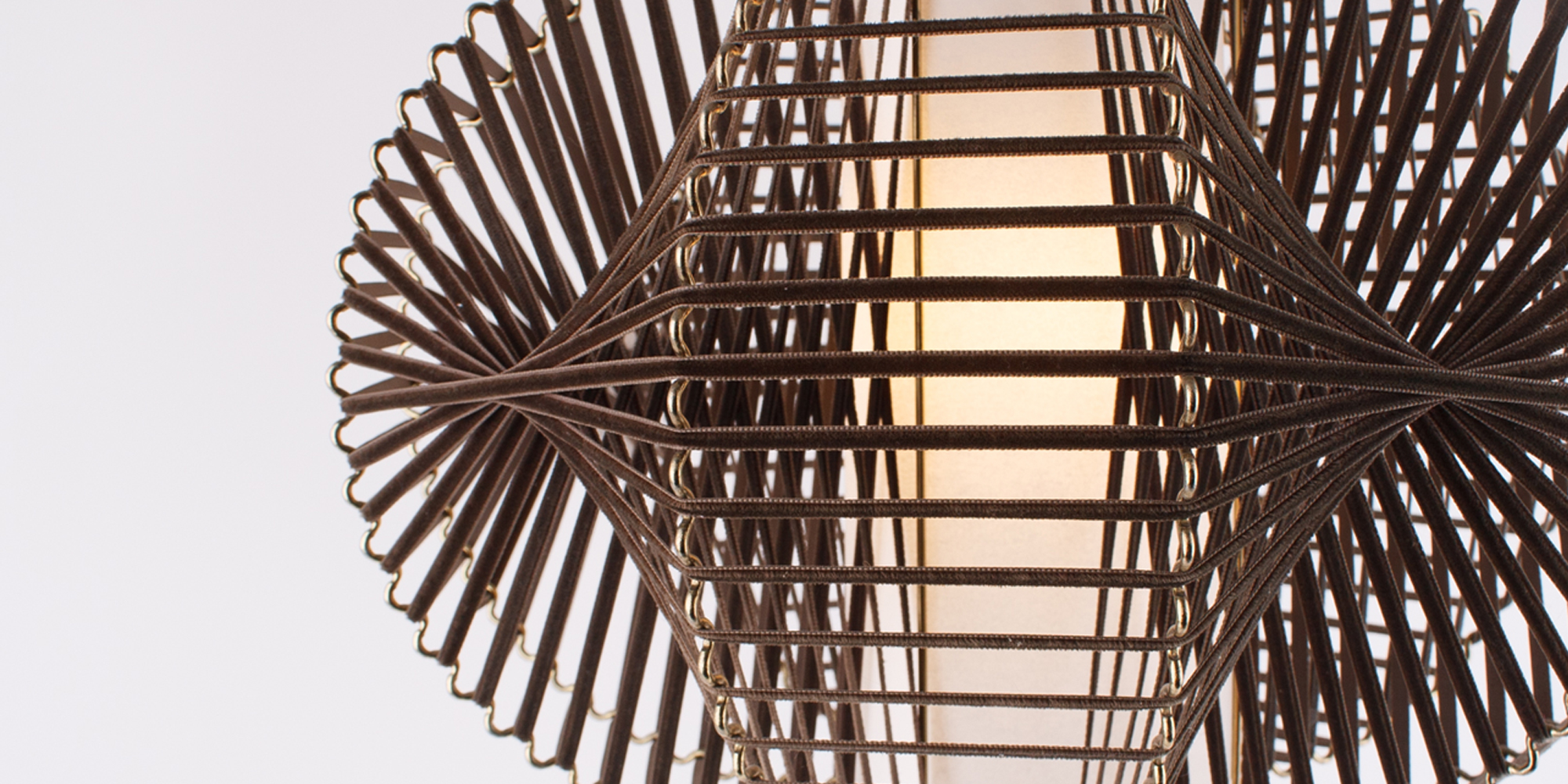 Eine Designlampe, bestehend aus Messing und Samtband. Die Art wie das Samtband auf den wellenartig geformten Draht gebunden ist, wirft ein tolles Licht auf die Zimmerwand. In der Mitte befindet sich ein Papier,das in Zilinderform das Leuchtmittel bedeckt und somit ein angenehmes Licht abgibt. Die Höhe der Lampe ist 30 cm und die breiteste Stelle an der Lampe ist 40 cm.